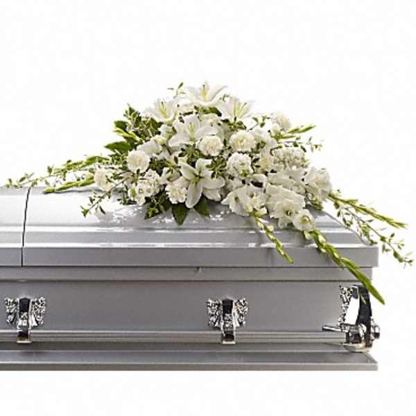 White floral casket spray on a gray casket