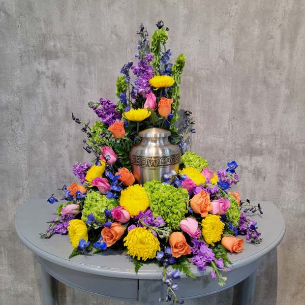 Colorful floral arrangement surrounding a silver urn on a table