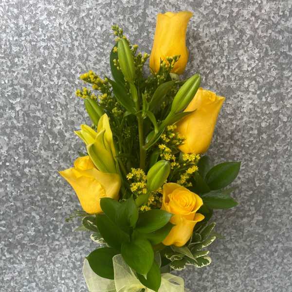 Yellow roses and lilies in a clear glass vase with a ribbon