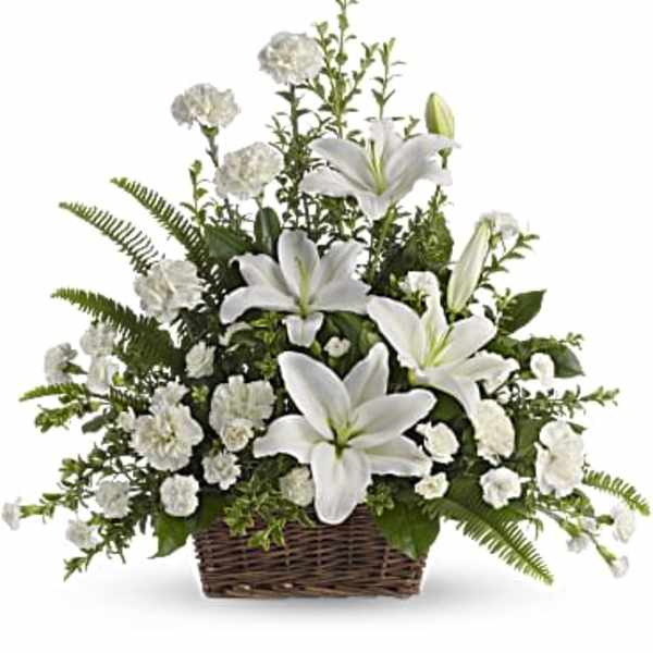 White lilies and carnations arranged in a brown wicker basket