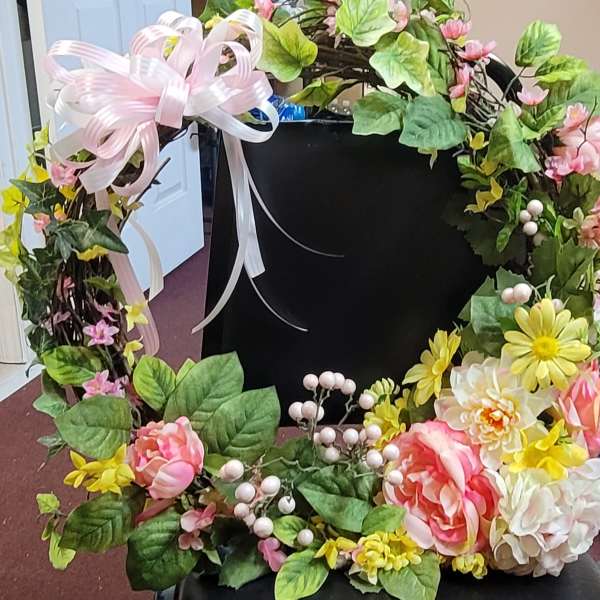 Floral wreath with pink ribbon, yellow daisies, and pink-and-white blooms