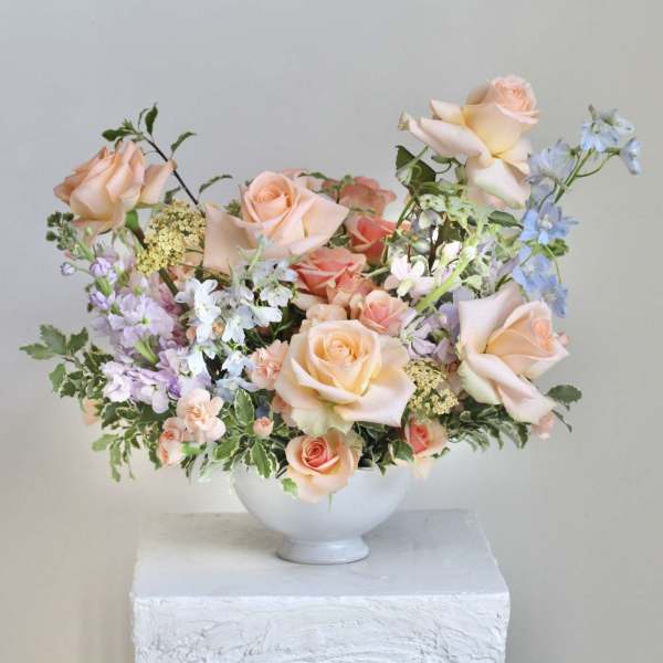 Peach roses and pastel flowers arranged in a white bowl vase