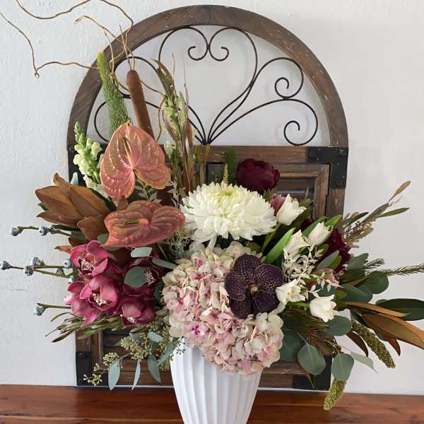 Mixed floral arrangement in a white vase with pink, white, and burgundy blooms