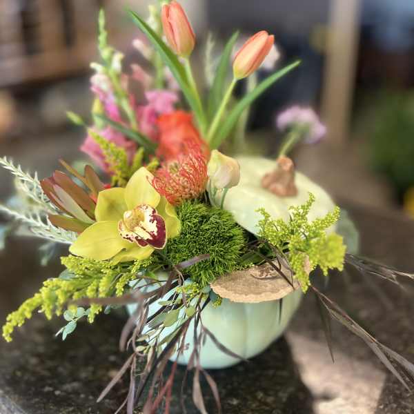 Colorful mixed flower arrangement in a pale mint container
