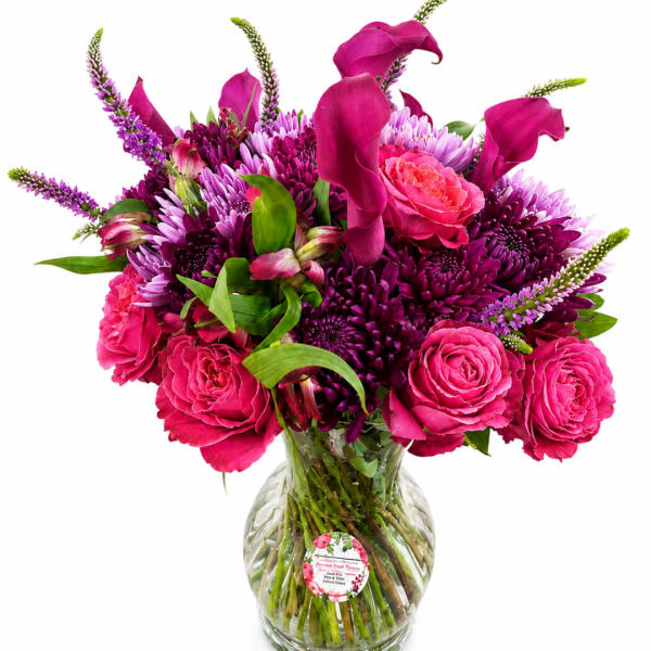 Pink and purple bouquet with roses, calla lilies, and chrysanthemums in a glass vase