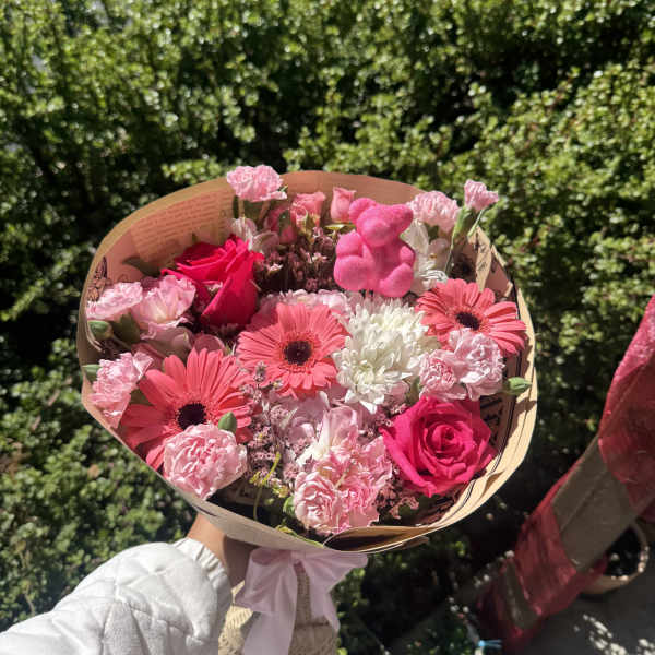 Pink mixed flower bouquet with roses and gerbera daisies wrapped in paper