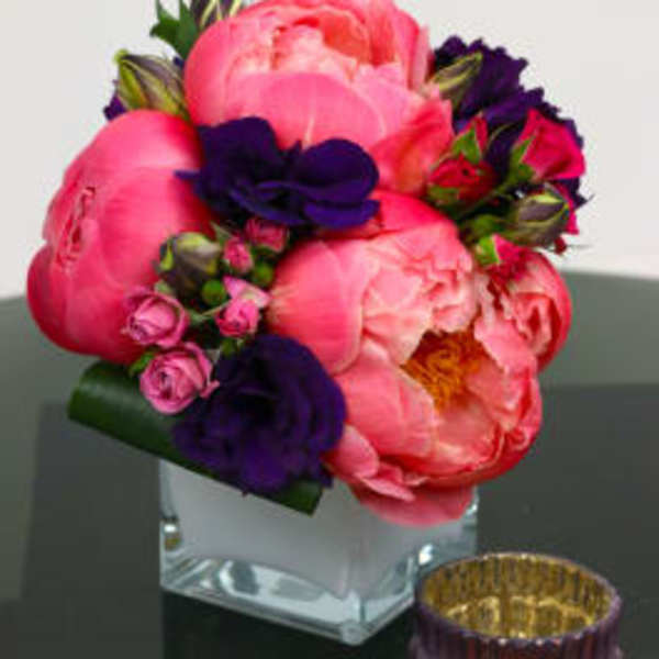 Pink and purple floral arrangement in a clear square vase