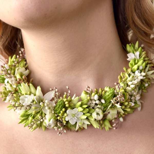 Floral necklace with white and green blossoms around a woman's neck