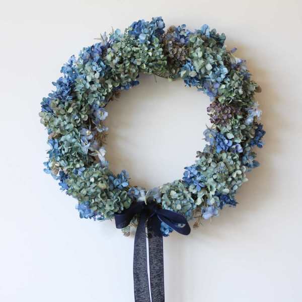 Blue and green floral wreath with a dark ribbon bow