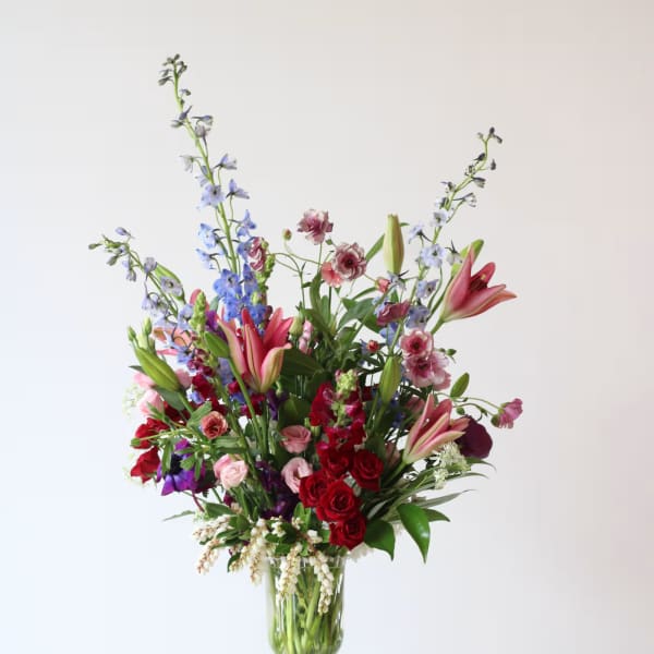 Tall mixed flower arrangement in a clear glass vase