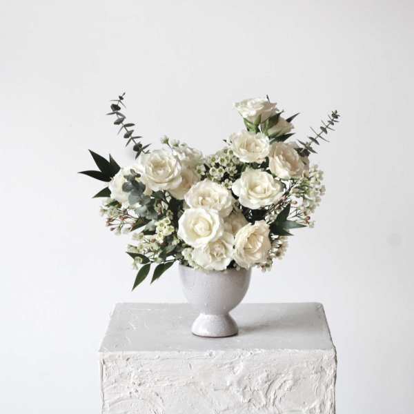 White rose arrangement in a gray pedestal vase