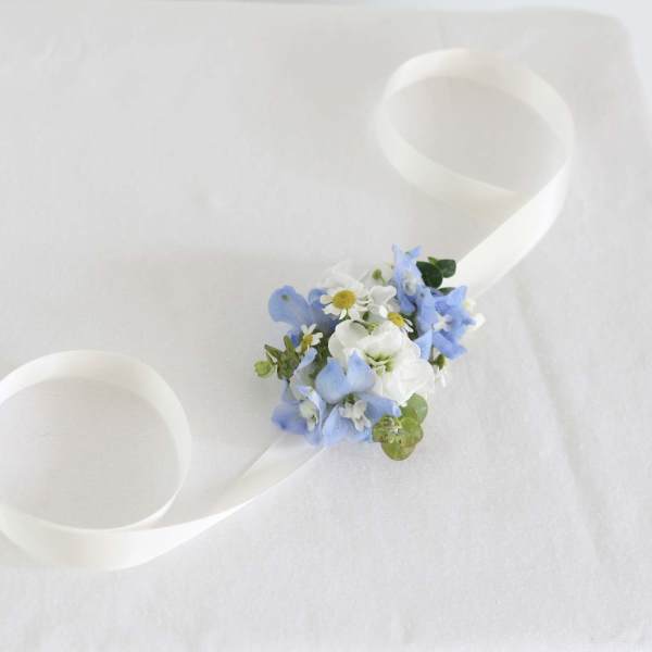 White ribbon wrist corsage with blue and white flowers