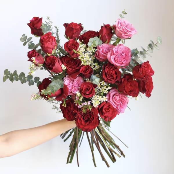 Handheld bouquet of red and pink roses with eucalyptus