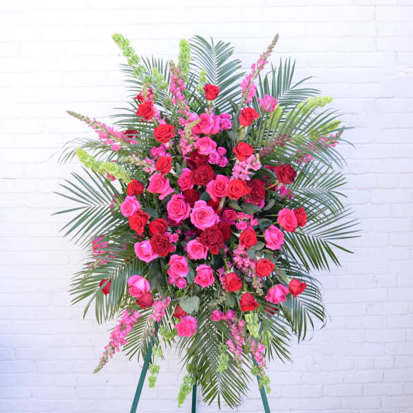 Large standing spray of pink and red roses with palm fronds