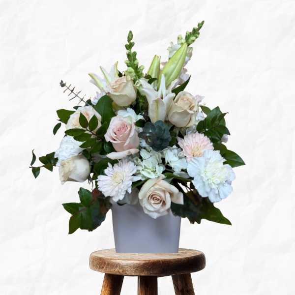 White and blush floral arrangement in a gray vase