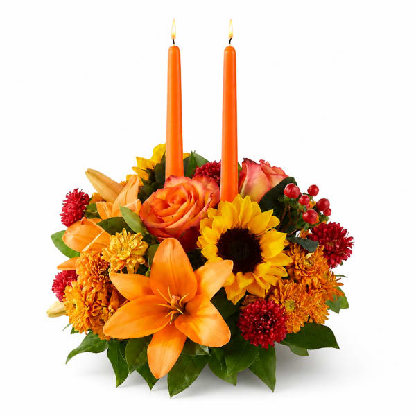 Orange floral centerpiece with two lit taper candles