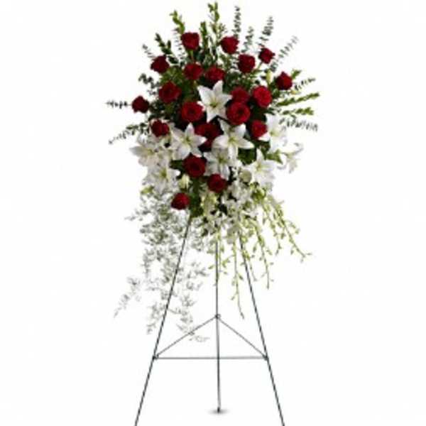 Tall standing spray of red roses and white lilies on a metal easel