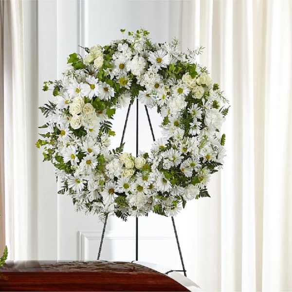 White floral wreath on a black easel stand