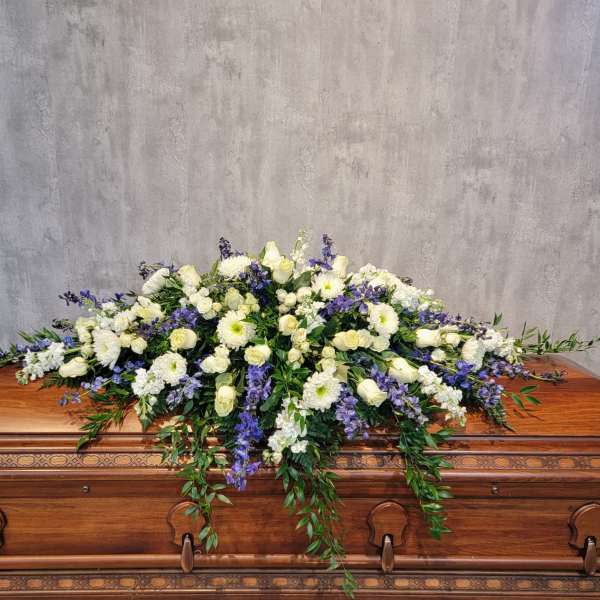 White and purple floral spray on a wooden casket
