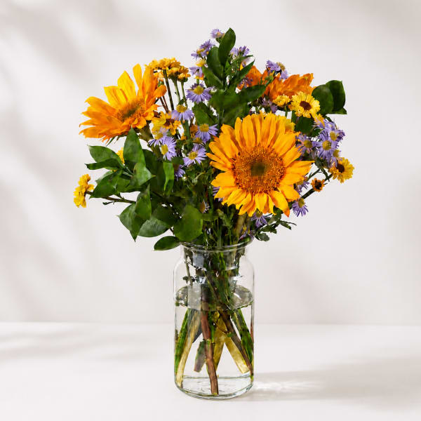 Yellow and purple mixed bouquet in a clear glass vase