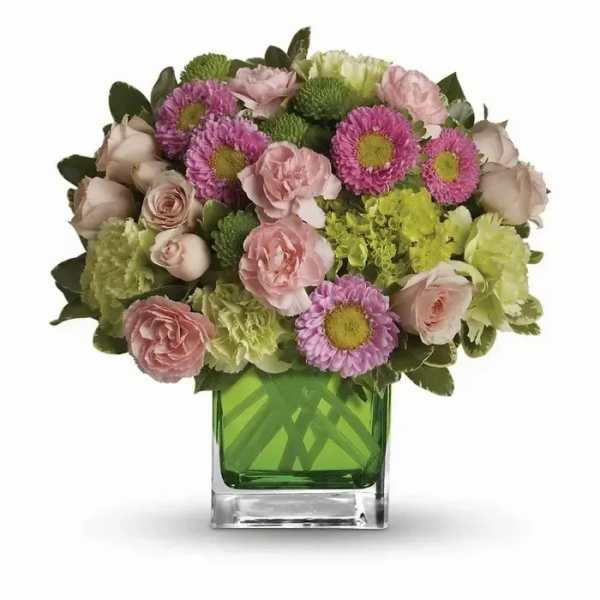 Compact arrangement of pink and green flowers in a clear cube vase with a bright green liner