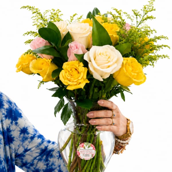 Bouquet of yellow, white, and pink roses in a clear glass vase