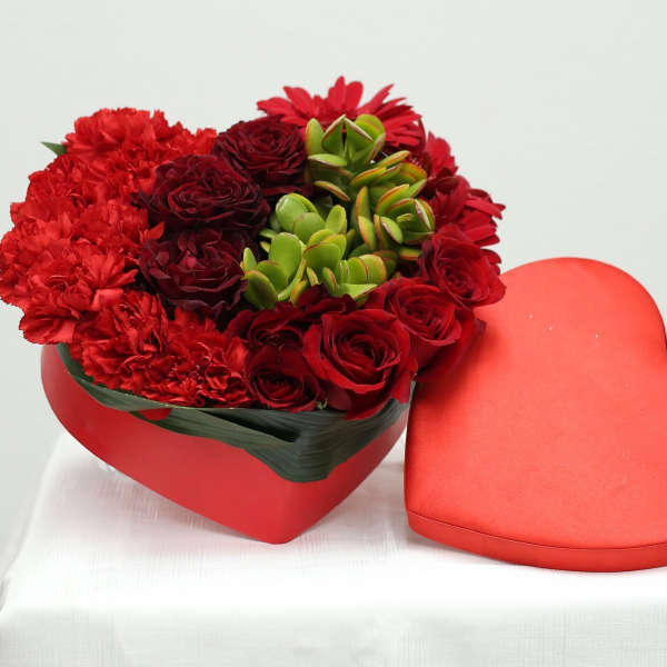 Heart-shaped box of red flowers with a matching heart lid beside it