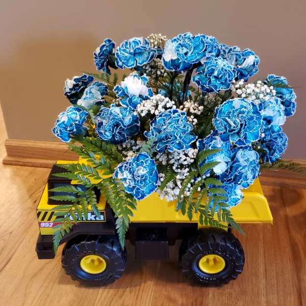 Blue carnations arranged in a toy dump truck with white filler flowers