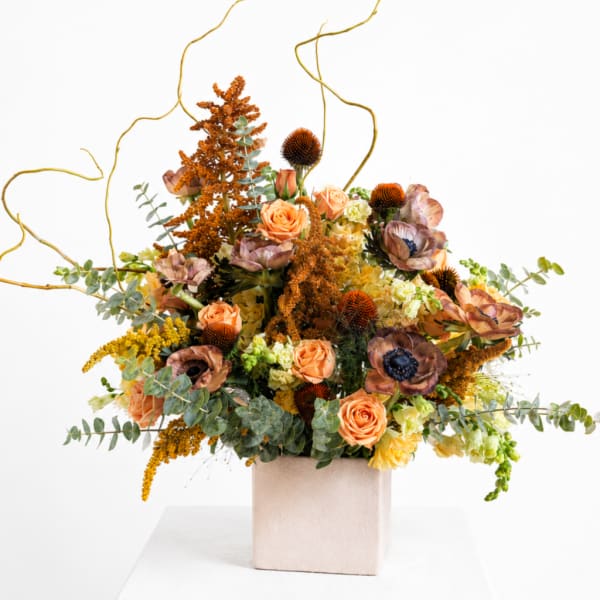 Peach roses and mixed autumn flowers in a square vase