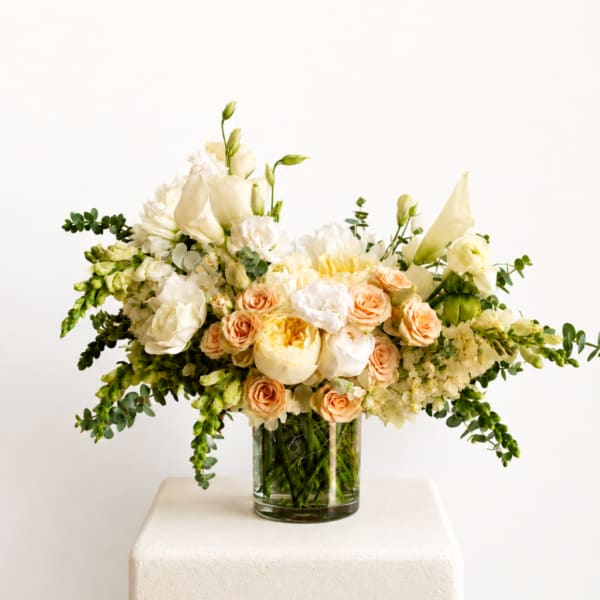 Cream and peach floral arrangement in a clear glass vase
