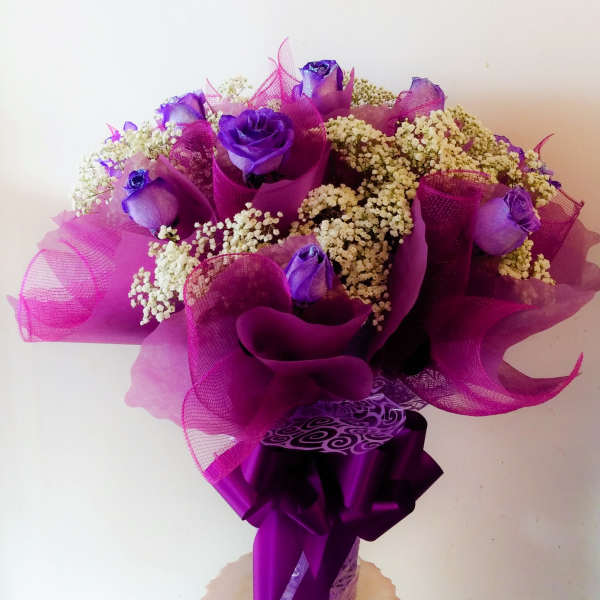 Purple roses with white filler flowers wrapped in magenta paper