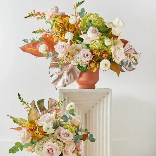 Two pastel floral arrangements in terracotta vases on pedestals