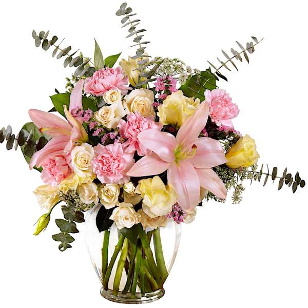 Pink lilies and roses in a clear glass vase with eucalyptus