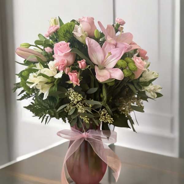 Pink and white mixed flower bouquet in a pink vase with ribbon
