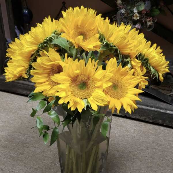 Bright yellow sunflowers arranged in a clear glass vase.