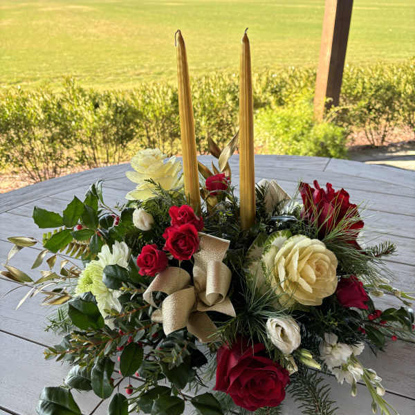 Floral centerpiece with red and cream roses and tall gold candles