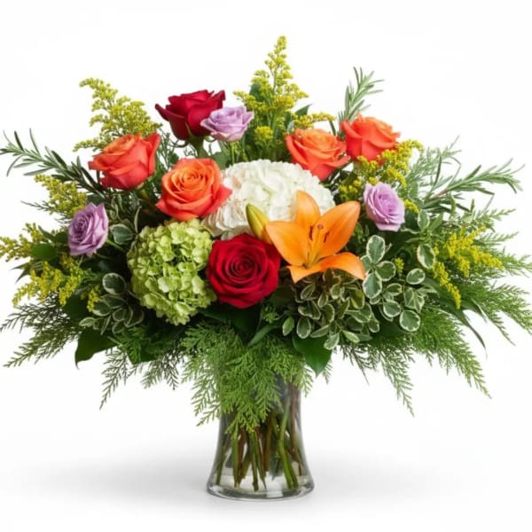 Mixed bouquet of roses, lilies, and hydrangea in a glass vase