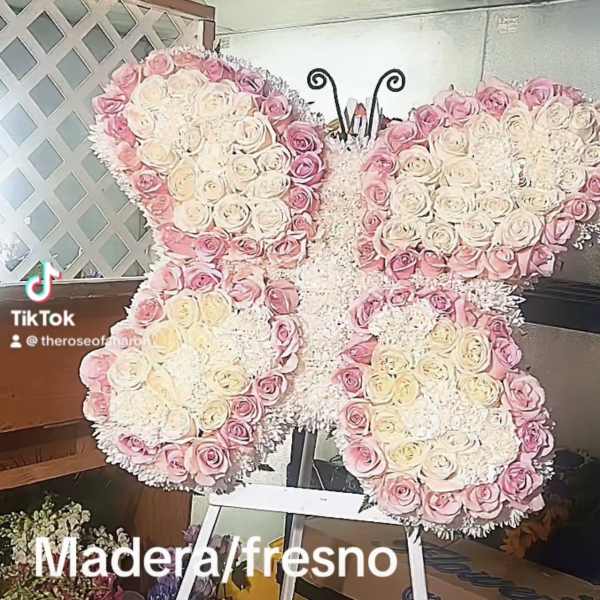 Butterfly-shaped floral arrangement of pink and white roses on an easel