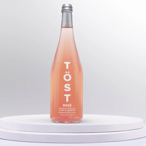 Bottle of TÖST rosé sparkling beverage on a white pedestal