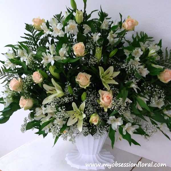 White and peach floral arrangement in a white pedestal vase