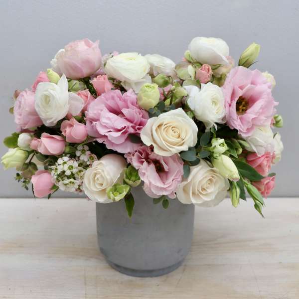 Low pastel arrangement of pink and white roses and lisianthus in a gray cylinder vase
