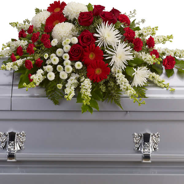 Red, white, and green floral spray on a silver casket