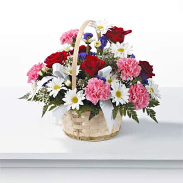 Basket arrangement of red roses, pink carnations, and white daisies