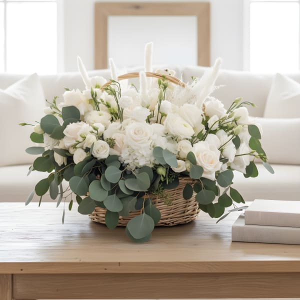 White floral arrangement in a wicker basket with eucalyptus
