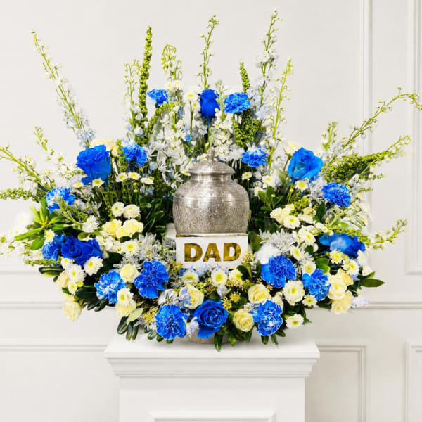 Blue and white floral arrangement around a silver urn with a "DAD" sign