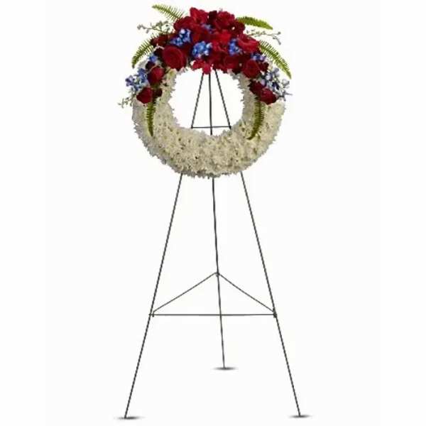 Standing funeral wreath with red, white, and blue flowers on a metal easel