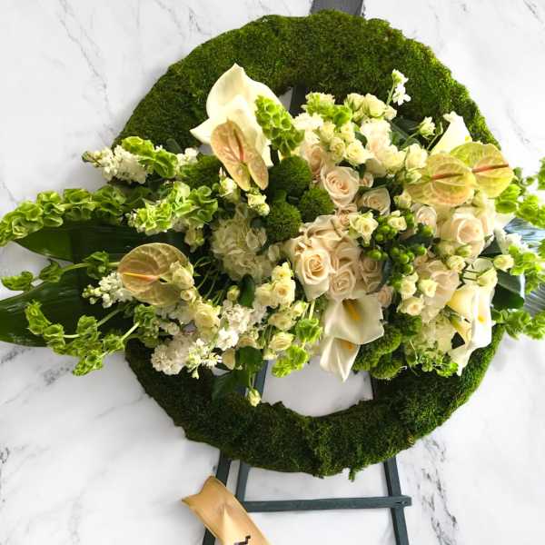 Cream and green funeral wreath with roses and calla lilies