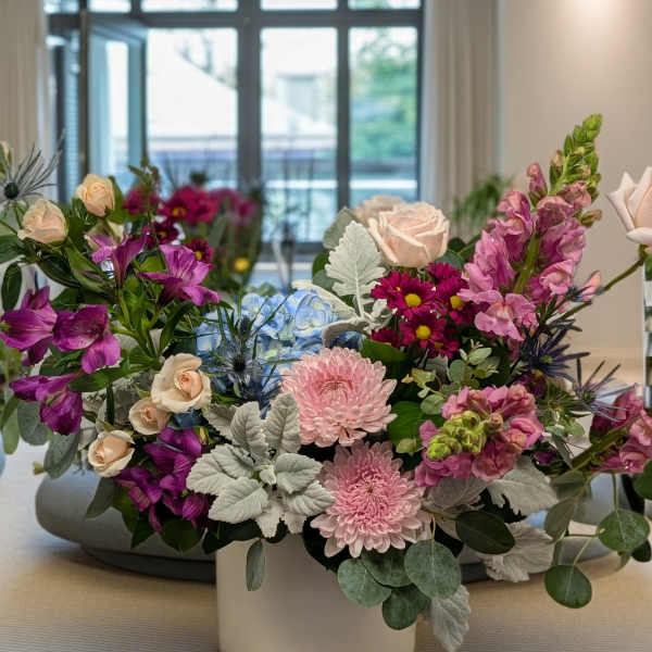 Mixed bouquet in a white vase with pink, purple, and blue flowers