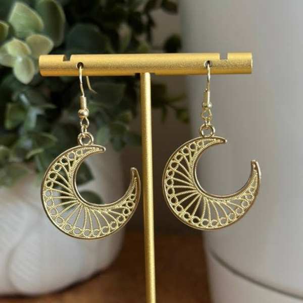 Pair of gold crescent moon earrings on a display stand