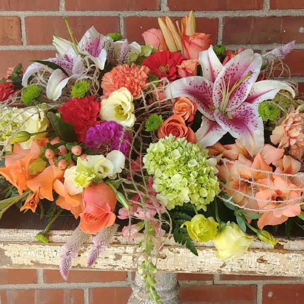 Large mixed floral arrangement with lilies, roses, and carnations in warm colors